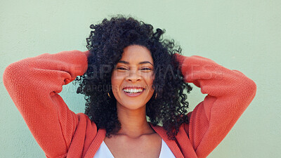 Freedom, hair and fun with a young woman playing with her curly hairstyle and laughing on a green wall background. Happy, funny and smile with an attractive and playful young female feeling carefree