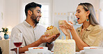 Interracial, couple and celebrate for birthday with gift, being happy and relax together at party. Romance, man and woman with present, bonding and smile in home in living room for hug and embrace.