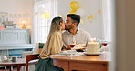 Couple, kiss and gift for birthday celebration, love and happy relationship together at home. Man and woman celebrating special day of birth in bonding happiness with cake and gifts at the table