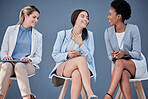 Human resources, technology and talking with business women waiting in line for a recruitment interview. HR, resume and conversation with a group of people sitting in a row for candidate hiring