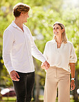 Love, park and a couple holding hands while walking together outdoor in nature while on a romantic summer date.  Trust, romance or affection with a man and woman bonding during a walk in the garden