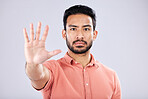 Stop, serious and portrait of an Asian man with a hand isolated on a grey studio background. Negative, no and Japanese guy with a gesture for rejection, deny and forbidden warning on a backdrop