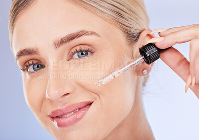 Buy stock photo Portrait, face and skincare of woman with serum in studio isolated on a blue background. Dermatology cosmetics, beauty closeup and happy female model apply hyaluronic acid, retinol or essential oil.