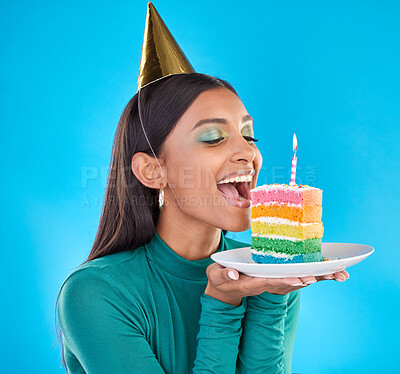 Buy stock photo Celebrate, birthday and woman in studio with a cake, party hat and candle for a celebration. Happy, smile and Indian female model ready to eat sweet rainbow dessert while isolated by blue background.