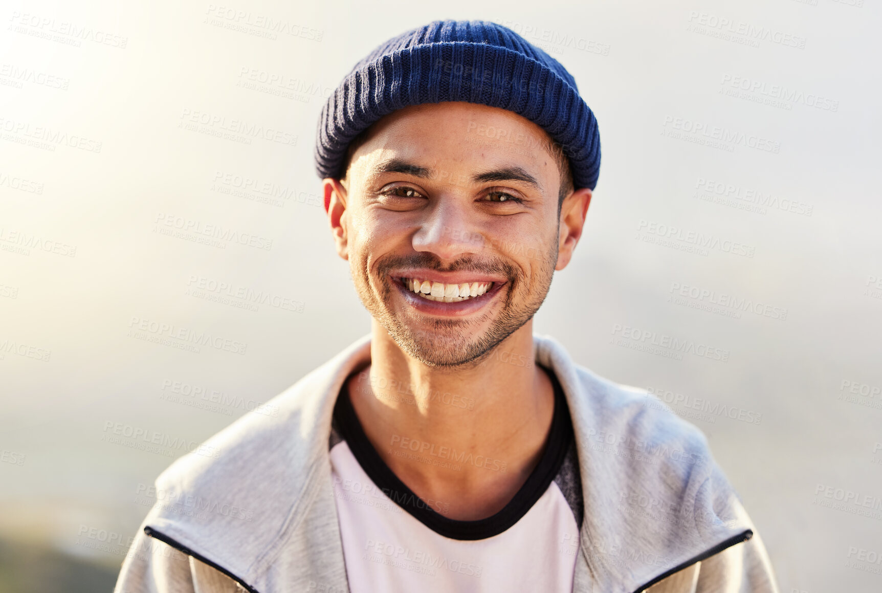 Buy stock photo Portrait, happy and nature with a man in a beanie, standing outdoor in the wilderness on a gray sky. Face, smile and lifestyle with a handsome young male outside for travel, freedom or adventure