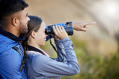 Buy stock photo Binoculars, pointing and a couple bird watching in nature while hiking in the mountains together. Forest, nature or sightseeing with a man and woman looking at the view while bonding on a hike