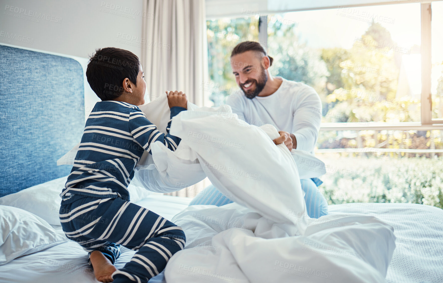Buy stock photo Love, father and son in bedroom, pillow fight and happiness on vacation, quality time and break. Family, dad and boy on bed, playful and smile for bonding, loving and carefree with joy and cheerful