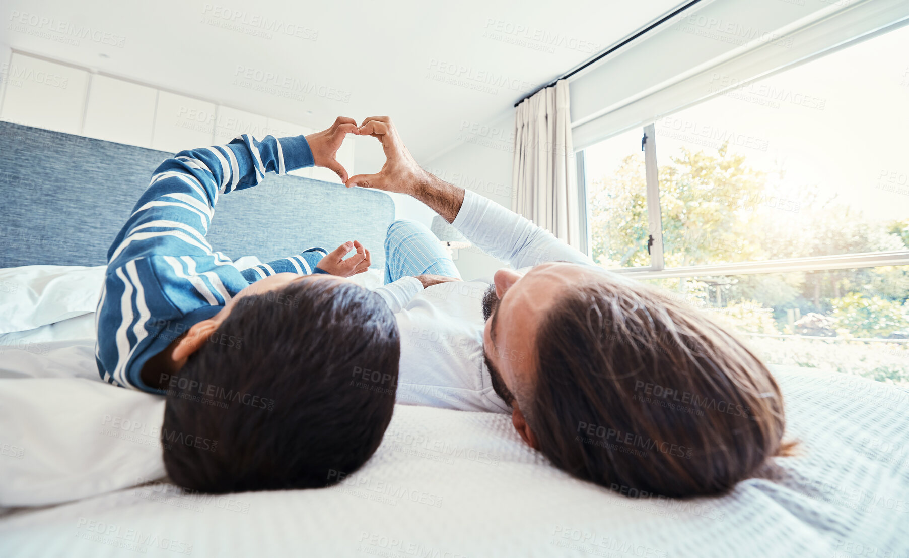 Buy stock photo Heart shape, father and son on bed, quality time and happiness on break, relax and bonding together. Family, dad and boy in bedroom, sign for love and resting with joy, carefree and loving in morning
