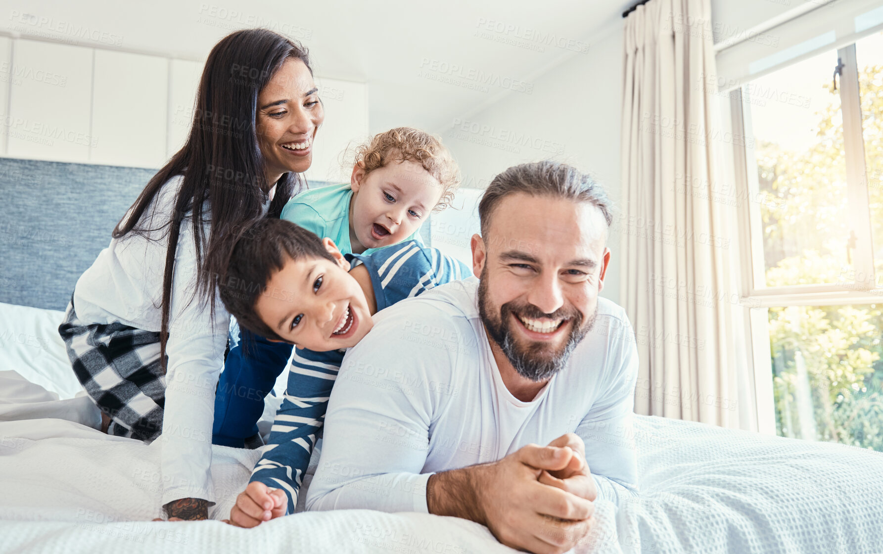 Buy stock photo Family, portrait and laughing on bed in home, having fun and bonding together. Comic, love and care of happy father, mother and kids or boys playing, smile and enjoying quality time in house bedroom.