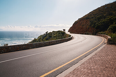 Buy stock photo Mountain, road and ocean view with no people for travel, destination or sightseeing in Cape Town. Nature, beauty on empty street for road trip, vacation or holiday on South Africa blue sky background