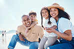 Family, portrait and smile at beach on vacation, having fun and bonding together. Holiday, relax and care of happy father, mother and kids or children by seashore enjoying quality time outdoors.