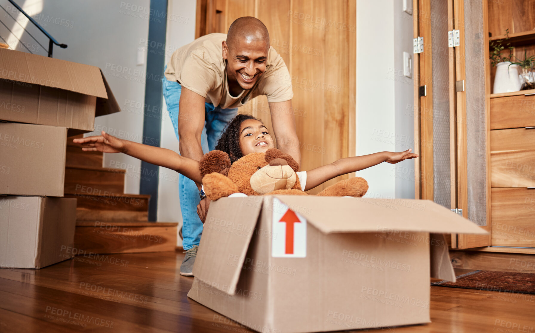 Buy stock photo New home, father and pushing girl in box, having fun and bonding after moving in house. Real estate, family property and child with teddy bear, boxes and happy dad playing to celebrate relocation.