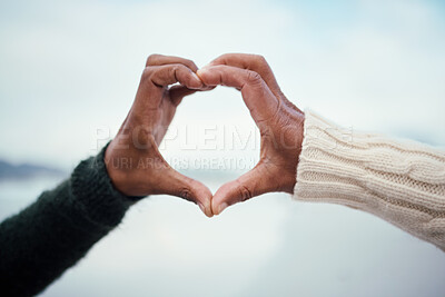 Buy stock photo Black couple, heart hands and love by the sea with support and care outdoor. Blurred background, beach and ocean adventure date of people together with romantic emoji hand sign in nature on holiday