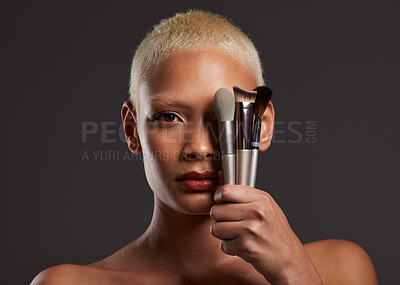 Buy stock photo Woman, portrait and makeup brushes for facial beauty cosmetics, skincare or treatment against a gray studio background. Beautiful female holding cosmetic brushing tools on face for self care or love