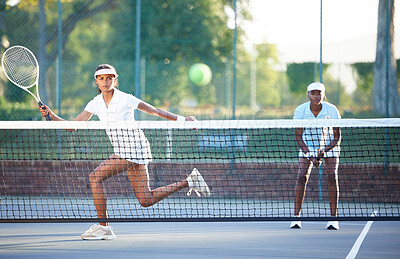 Buy stock photo Tennis, fitness and a sports woman hitting a ball over a net during a competitive game to return a serve. Exercise, health or training with a female athlete and doubles partner playing on a court