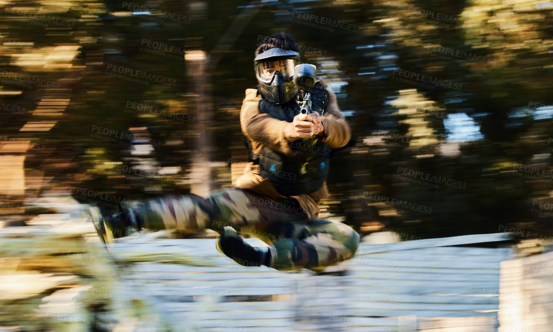 Buy stock photo Action, paintball and man shooting and jumping on battlefield with a gun in a game, match or training. Shooter, blur motion and male with strategy in military aim and shoot target outdoors