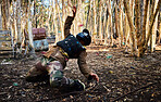 Man, paintball and dodging shots in the matrix for intense battle or war in the forest on knees. Male paintballer or soldier ducking to dodge paint balls in extreme adrenaline sports outdoors