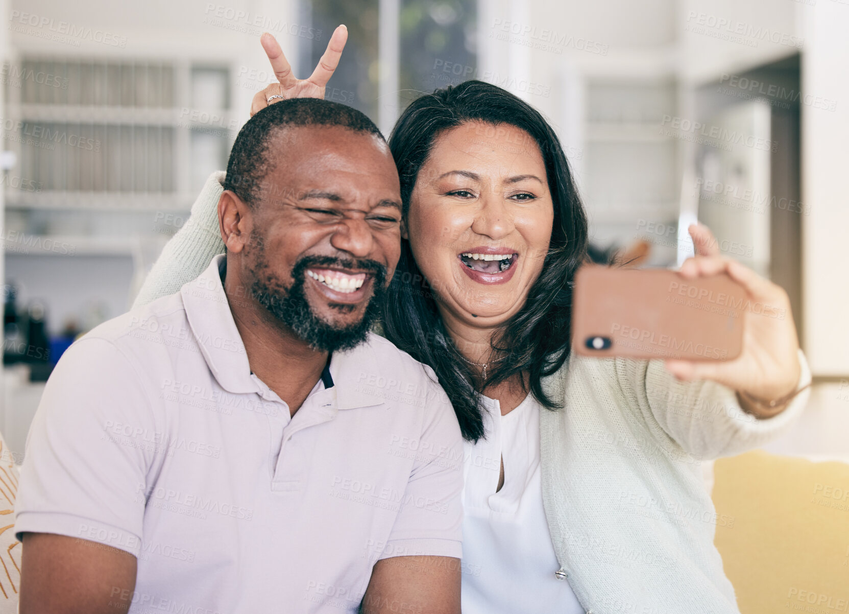 Buy stock photo Senior black couple, selfie or happy in home together for silly, social media or relax with peace sign hand. Mature man, woman and digital photography app in house for embrace, bonding and bunny ears