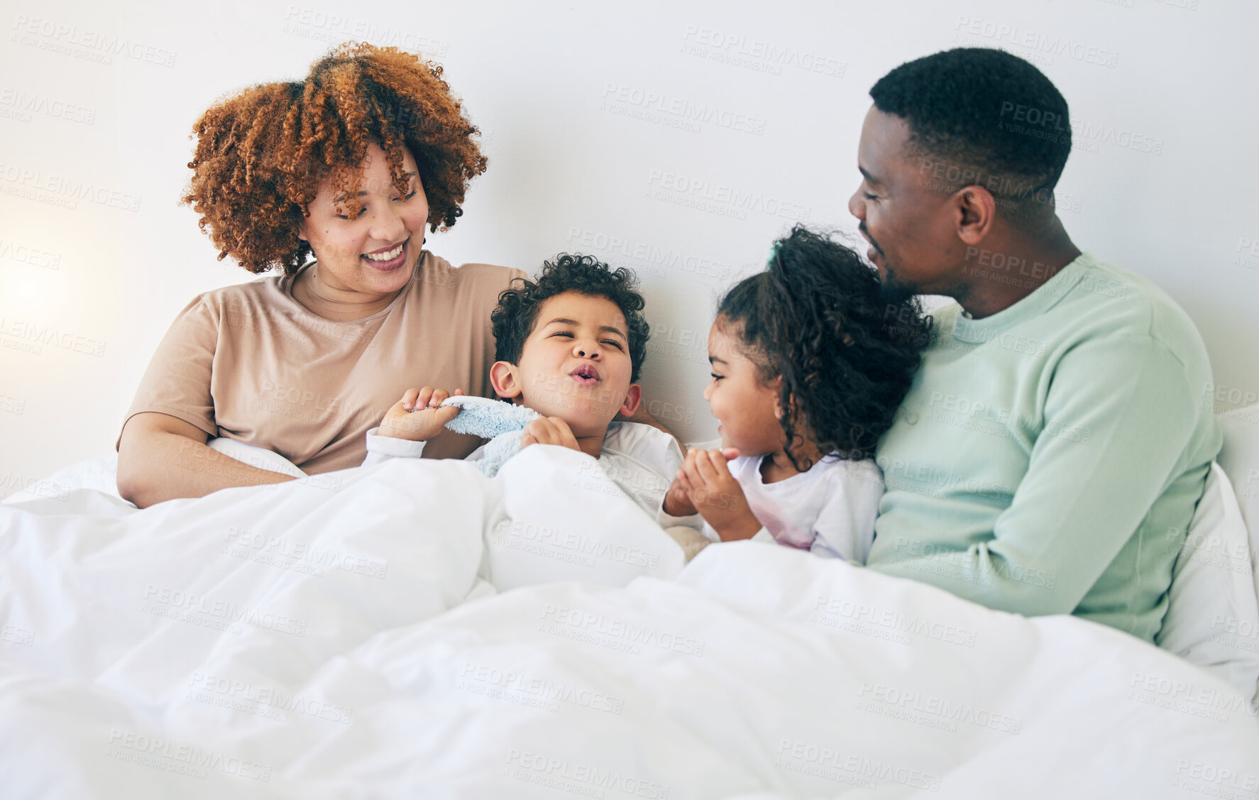 Buy stock photo Happy, love and parents with children in bed enjoy morning for bonding, quality time and relaxing. Black family, bedroom and mother, father and kids playing on holiday, weekend and vacation at home