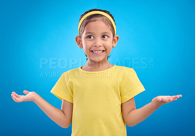 Buy stock photo Girl, child and shrug with happy or unsure face in studio with arms and hands stretched with a smile. Kid on blue background clueless, doubt and confused about question or reaction with hand gesture