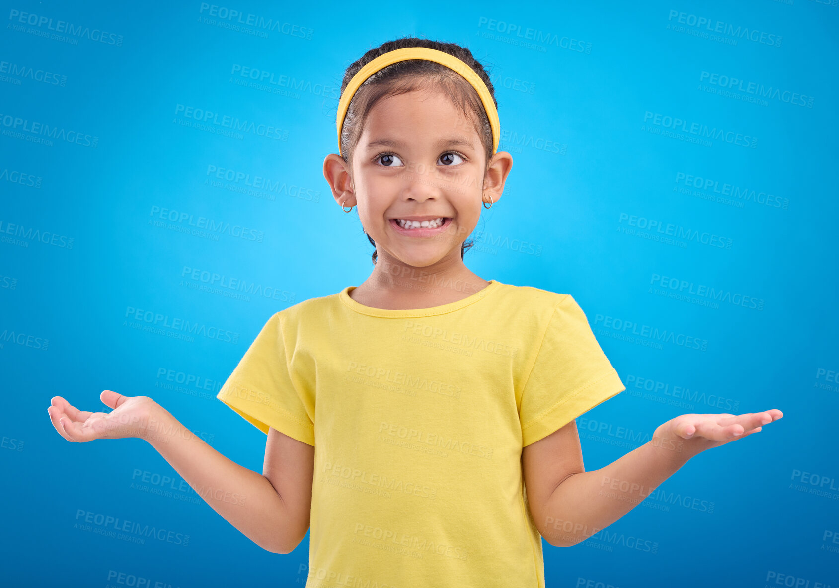 Buy stock photo Girl, child and shrug with happy or unsure face in studio with arms and hands stretched with a smile. Kid on blue background clueless, doubt and confused about question or reaction with hand gesture