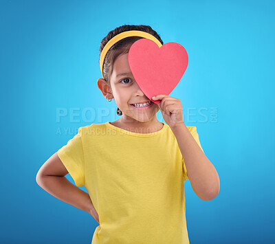 Buy stock photo Portrait, heart cut out and girl with smile, joyful and cheerful against blue studio background. Face, female kid and young person with symbol for love, happiness and joyful with development and sign