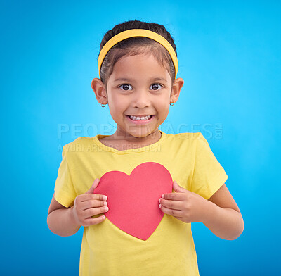 Buy stock photo Portrait, smile and girl with heart cutout, joy and cheerful against a blue studio background. Face, Indian female child and kid with love symbol, excited and young person with sign, mockup and happy