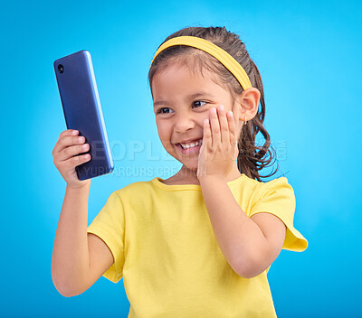 Buy stock photo Wow, excited and girl with smartphone, social media and cheerful kid against a blue studio background. Latino female, happy young person and cellphone with connection, happiness and watching video