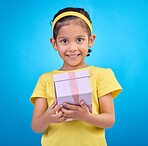 Gift, box and smile with portrait of girl in studio for celebration, shopping and birthday event. Happiness, surprise and present with child for party, giveaway or product isolated on blue background
