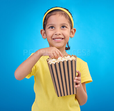 Buy stock photo Popcorn, eating and watching movie with girl in studio for food, cinema and comedy. Laugh, television and film with child and snack for streaming, subscription and tv isolated on blue background