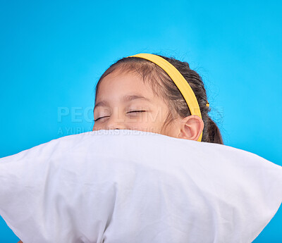 Little girl, pillow and sleep in a studio feeling tired, fatigue and ready for dreaming. Isolated, blue background and happy young child with pillows and closed eyes for sleeping, rest and nap