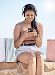 Woman relax after shopping, smartphone and headphones, listening to music outdoor with retail therapy and rest. Happy female, paper bag and communication with chat on social media app and technology