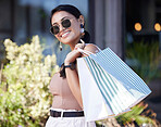 Woman with shopping bag, retail and fashion with outdoor mall, happy customer with freedom in city. Luxury with sale, discount and deal at boutique, female with smile for store product and commerce