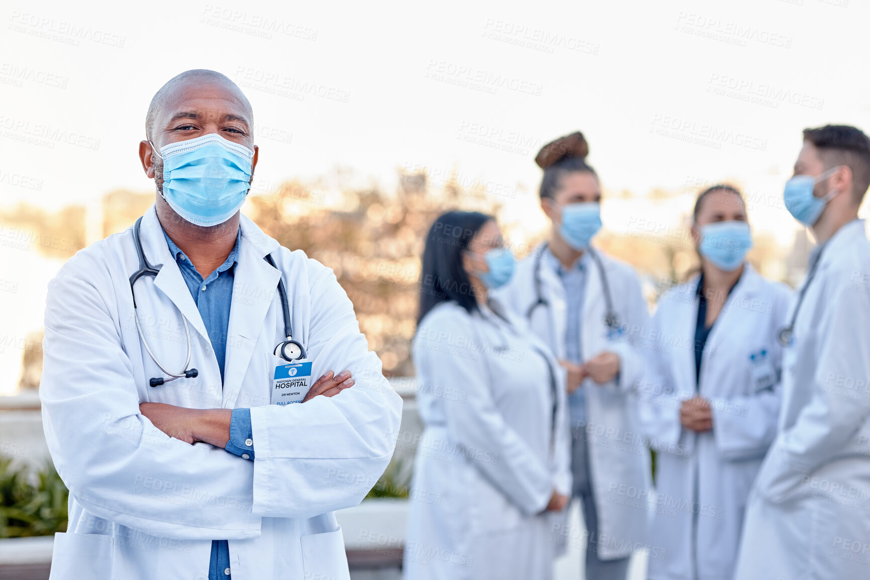 Buy stock photo Covid, portrait and proud man doctor outside of hospital with team for planning, teamwork and strategy. Face, healthcare and male leader with doctors for innovation, brainstorm and corona management