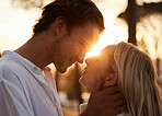 Couple, love and kiss outdoor at sunset for love, care and romance with hands on face on a date. Young man and woman together on valentines day with lens flare, peace and freedom in nature forest