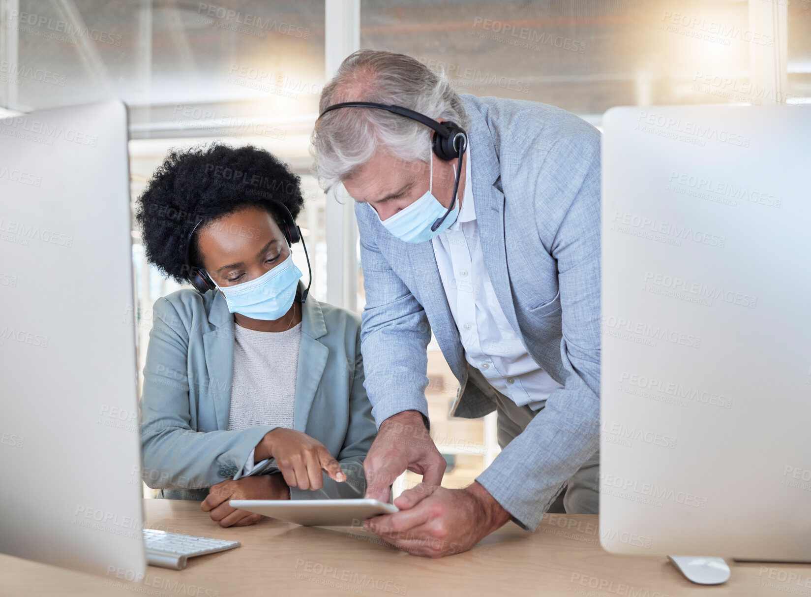 Buy stock photo Covid, crm and employees with tablet, mask and senior man helping black woman at call center help desk. Compliance, consulting and opinion, crm data for medical advisory agency with coaching support.