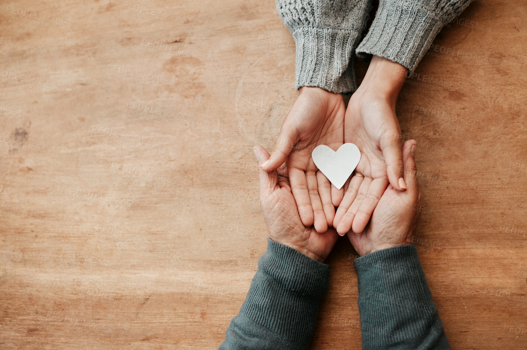 Buy stock photo Hands, heart and shape for love, support or care above in trust, unity or compassion together on mockup table. Top view of hand holding for family generation, hope or symbol in bonding relationship