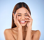 Beauty, cosmetics and portrait of woman laughing with hands on face in studio for skincare promo on blue background. Makeup, facial and cosmetics, hispanic model from Brazil for dermatology promotion