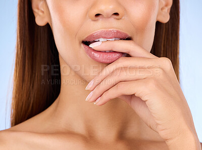 Buy stock photo Skincare, mouth and woman biting finger in studio zoom isolated on blue background for lip care. Natural beauty, luxury cosmetics and bite on hand, face closeup of hispanic model with makeup on lips.