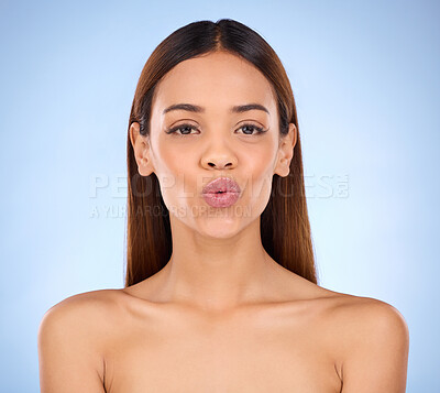 Buy stock photo Beauty, cosmetics portrait and lips kiss with a model pout with lip gloss makeup in studio. Cosmetic, mouth and natural glow of a woman with clear and smooth skin with isolated blue background