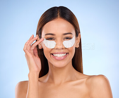 Buy stock photo Skincare, beauty and portrait of happy woman with eye mask for anti aging or skin glow on blue background. Cosmetics, facial repair pads and face of model with collagen product and smile in studio.