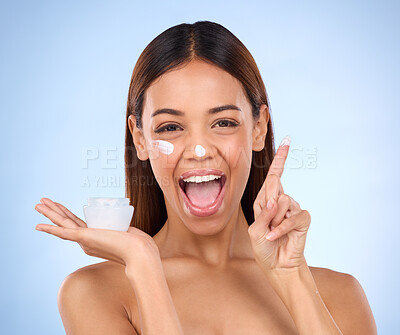 Buy stock photo Skincare portrait of excited woman, cream on finger and anti aging skin care on blue background. Cosmetics, facial and face of hispanic model with moisturizer solution or collagen product in studio.