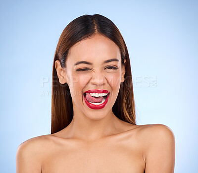 Buy stock photo Wink, woman and red lipstick makeup portrait with cosmetics on face in studio. Aesthetic female model on a blue background for self care, facial glow and beauty or color for skin with tongue out