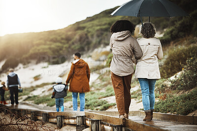 Buy stock photo Back, nature and a family walking on a wooden path outdoor together for holiday or vacation. Love, environment and bonding with relatives taking a walk near the beach while bonding in winter