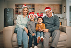 Portrait of grandparents with children in christmas hats relaxing on sofa in the living room. Happy, love and elderly couple sitting with kids with festive, holiday or xmas accessories at family home