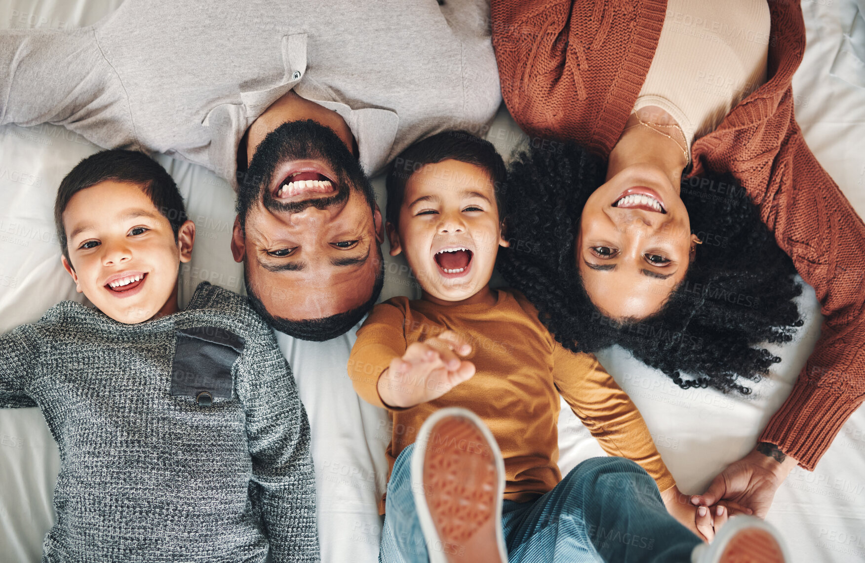 Buy stock photo Laughing, above and portrait of a family on a bed for relaxation, bonding and quality time. Playful, smile and carefree parents with children in the bedroom to relax and play in the morning together
