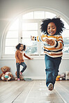 Hopscotch, happy and children play in home having fun, enjoying games and relax together in room. Childhood, entertainment and excited girl in bedroom for jumping game, playing and activity on floor