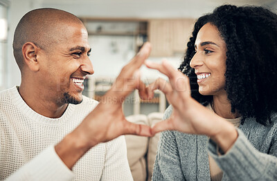 Buy stock photo Happy, love and hand heart by couple on sofa with love, care and trust at home together. Emoji, shape and man with woman hands in support of hope, marriage and unity, smile and joy in living room