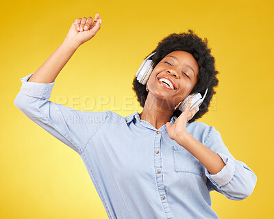 Buy stock photo Black woman, dancing with headphones and freedom, music and happiness on yellow studio background. Happy female, carefree and dance along to radio, audio streaming with fun and energy with technology