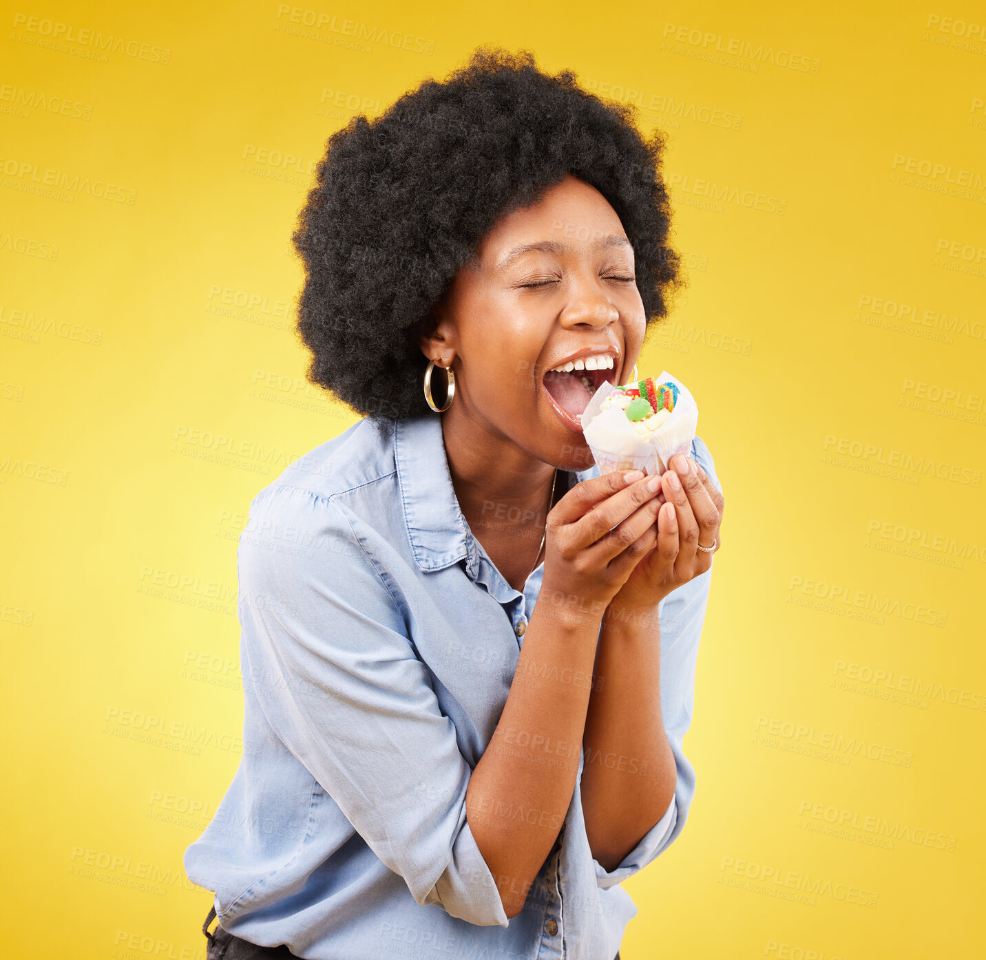 Buy stock photo black woman, cupcake and excited or happy in studio while eating sweet food on a yellow background. African female model with snack, dessert or cake for happiness, birthday or celebration mockup